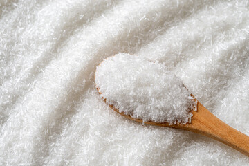 Monosodium glutamate in a wooden spoon over E621 white crystals background. Full spoon of MSG...