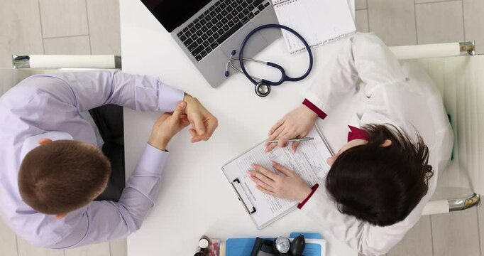 Orthopedic doctor examines man sore wrist and performs therapeutic exercise