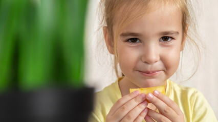 Naklejka premium Little girl eating an apple in her room at home