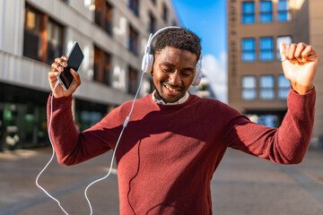 Happy african man listening to music with mobile and headphones