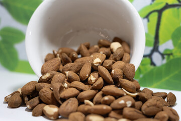 White Ceramic Mug with Unshelled Whole Almonds Pouring out