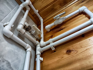 Detailed view of white plumbing pipes installed within wooden wall structure in a residential area