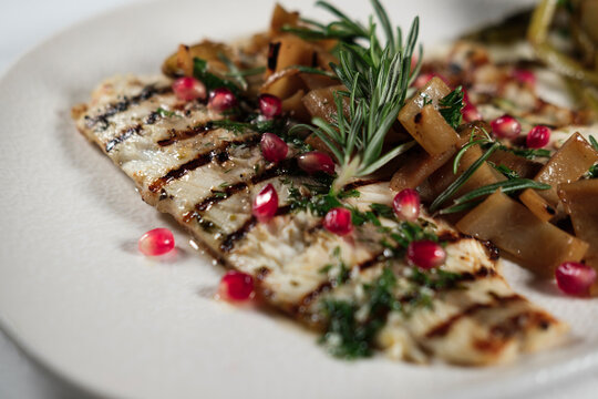 grilled juicy seabass served with butter garlic sauce, mediterranean herbs, sevketi bostan called holy thistle and pomegranate seeds