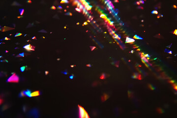 Colorful light refractions on dark background. Abstract, vibrant, textured light overlay. Multicolored triangles scattered. Cinematic sparkling particles in the air, iridescence festive light effect