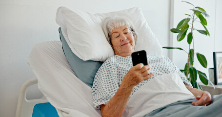 Senior woman, hospital and smile with smartphone for messages, recovery and healing in bed. Mature...
