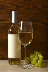 Fototapeta premium Bottle of white wine with grapes, glass, corkscrew and corks on wooden background