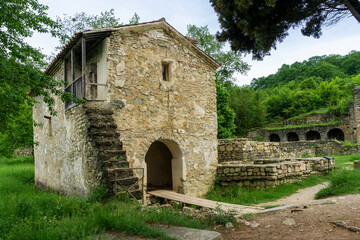 Obraz premium A small church on the grounds of Ikalto Academy. Stone walls and stairs, arched entrance. Green grass, sky with clouds.