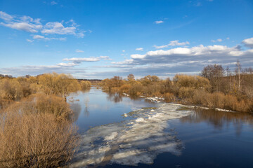 Fototapeta premium River with ice floating on it and trees in the background