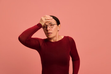 Pensioner, woman holding hand on head, feeling bad, pain disease against pastel peach background....