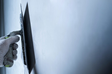 Worker uses a trowel to apply epoxy adhesive on a wall for repair.