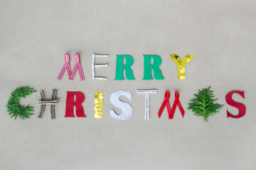 Handmade Merry Christmas greeting with capital letters made from various materials and juniper leaves