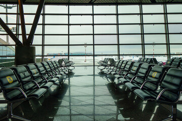 An empty airport waiting room. Airplanes can be seen outside the window in the background