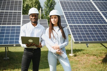 Group of multi ethnic people and safety helmets staring at solar farm.