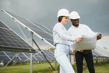 Group of multi ethnic people and safety helmets staring at solar farm.