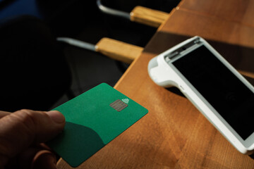 A man accepts payment from a customer through a credit card terminal in a store or cafe