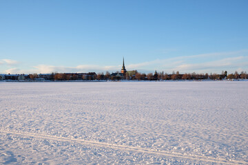 Winter landscape in Mora, Dalarna, showcasing snow-covered terrain and distant church tower