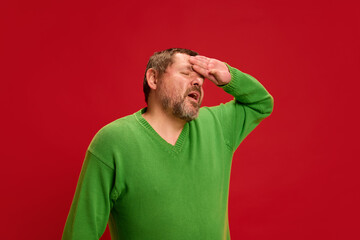 Portrait of mature man dressed casual and holding hand on head as feeling dizziness, as he will...