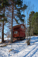 Winter landscape in Västanvik, Dalarna showcases a charming red wooden cabin