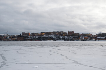 Snowy landscape of Stockholm with frozen water and colorful buildings in winter