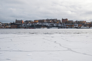 Winter landscape in Stockholm with snowy waterfront and calm water reflections