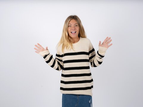 Optimistic Beautiful teen girl wearing striped sweater raises palms from joy, happy to receive awesome present from someone, shouts loudly,