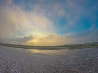 Obraz premium A completely frozen lake in the morning at sunrise. Typical Dutch rural landscape in winter season