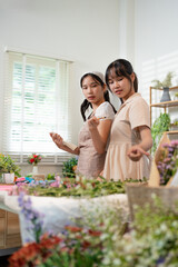 Naklejka premium happiness smiling young lady making flower vase.Self employed florist working at flower shop.young asian florist making list from client order to arrange flower bouquet vase delivery