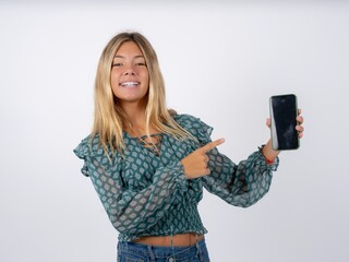 Naklejka premium Attractive cheerful Beautiful teen girl wearing green fashion T-shirt holding in hands cell showing black screen