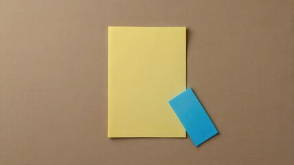 Fototapeta premium Yellow notepad with a blue sticky note on a beige background