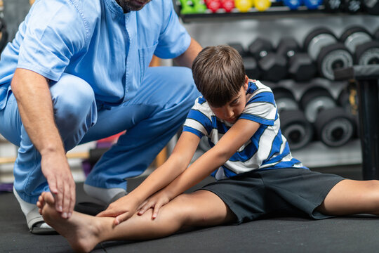 Physical therapist instructing a young boy in exercises, focusing on improving mobility, strength, and balance during a personalized rehabilitation session