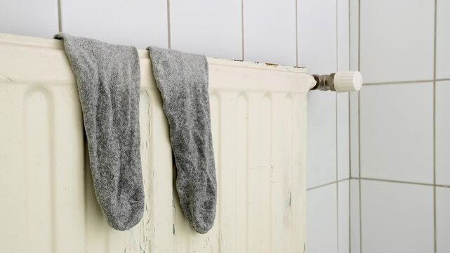 Pair of wet socks drying on a radiator in a bathroom. Timelapse