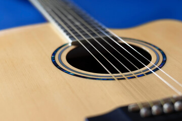 Fototapeta premium Close-up acoustic guitar on blue background. Selective focus