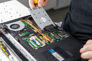 removing a hard drive from a laptop during disassembly for upgrade or replacement, close-up of...