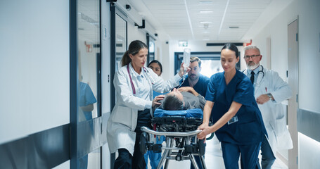 Diverse Emergency Medical Team Rushing Down a Hospital Corridor, Carefully Pushing a Stretcher with...