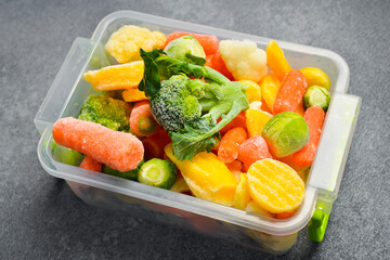 Frozen mix of vegetables in a plastic box. Preparation of frozen vegetables for the winter. On a...