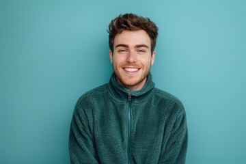 Fototapeta premium Portrait of a cheerful man in his 20s dressed in a comfy fleece pullover on solid color backdrop