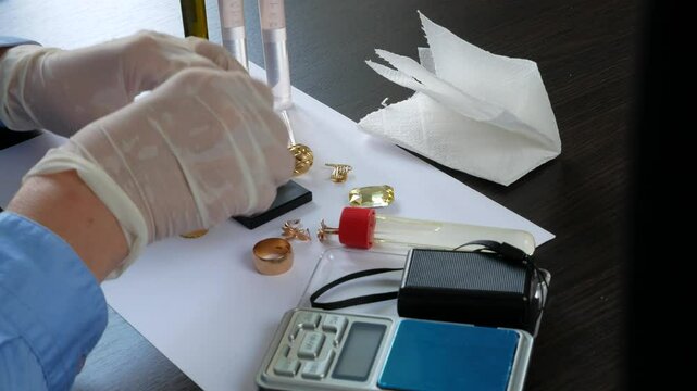 A pawn shop employee tests old gold jewelry using reagents and a touchstone, Buying old gold