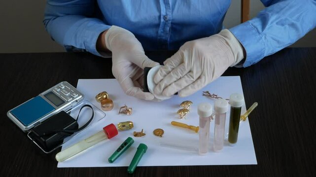 A pawn shop employee tests old gold jewelry using reagents and a touchstone, Buying old gold