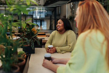 Coworkers chatting and drinking coffee in a green office