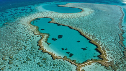 Obraz premium Top View of Tiny Isolated Sandbar Surrounded by Crystal-Clear Turquoise Waters with Coral Patterns