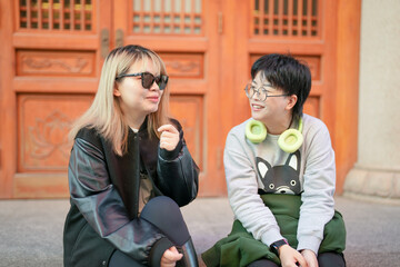 On a cold winter day in December 2024, two Chinese women in their 30s sit and talk in front of a historical building in Jing'an District, Shanghai, China.