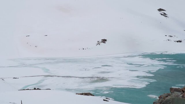 Frozen Suraj Tal lake during winter season at Lahaul, Himachal Pradesh, India. Cold frozen lake in Himalaya mountains.  Frozen lake surrounded with snowcapped mountains