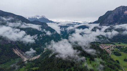 Fototapeta premium Mountain Serenity: Aerial View of a Scenic Village Amidst Clouds and Peaks
