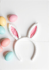 Fototapeta premium White bunny ears headband with pastel Easter eggs on table