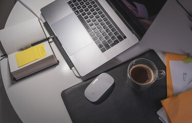 A laptop is on a table with a mouse and a cup of coffee