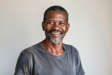 Fototapeta premium Portrait of a grinning afro-american man in his 50s dressed in a casual t-shirt isolated in plain white digital canvas