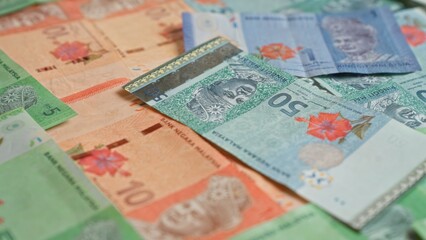 Malaysian ringgit banknotes scattered on a flat surface showcasing various denominations and...