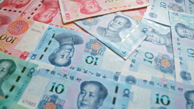 Chinese yuan banknotes spread out in a scattered pattern, showcasing different denominations and highlighting the vibrant colors and detailed designs of china's currency.