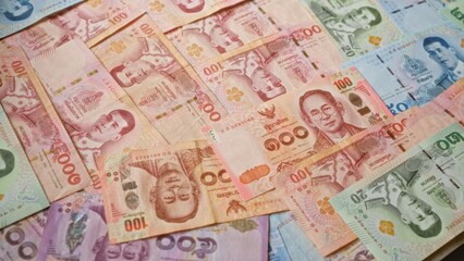 Obraz premium Various colorful thai baht banknotes spread out showcasing thailand's currency, highlighting intricate details and vibrant designs.