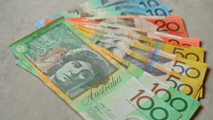 Australian banknotes in various denominations are spread out on a concrete surface, showcasing vibrant colors and intricate designs.